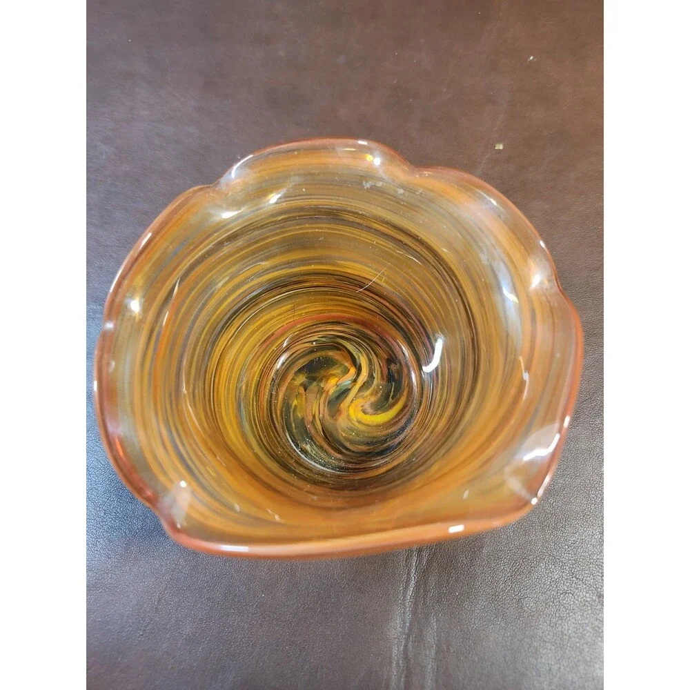 hand-blown art glass bowl features a vibrant orange and amber swirl pattern with